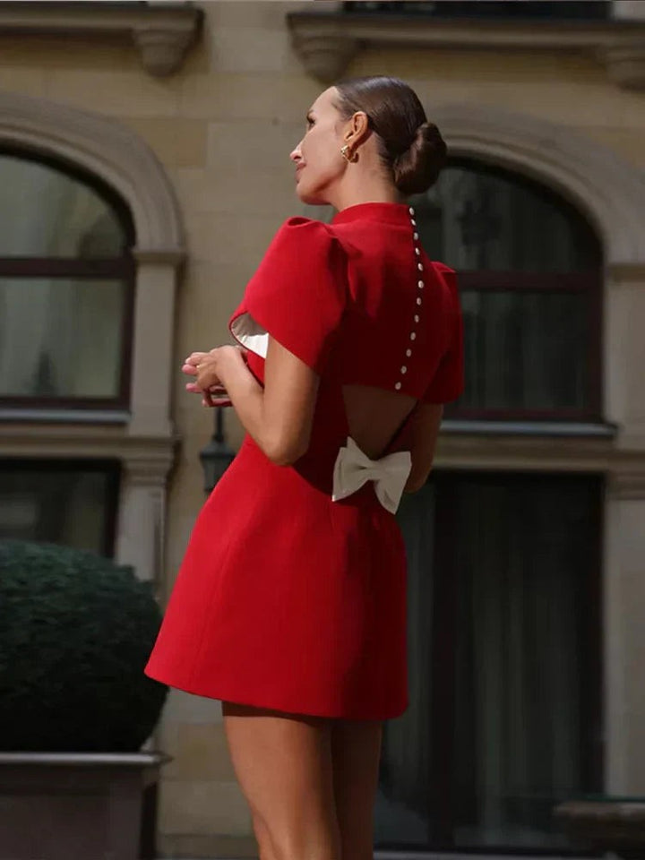Backless red mini dress featuring bow detail and button trim