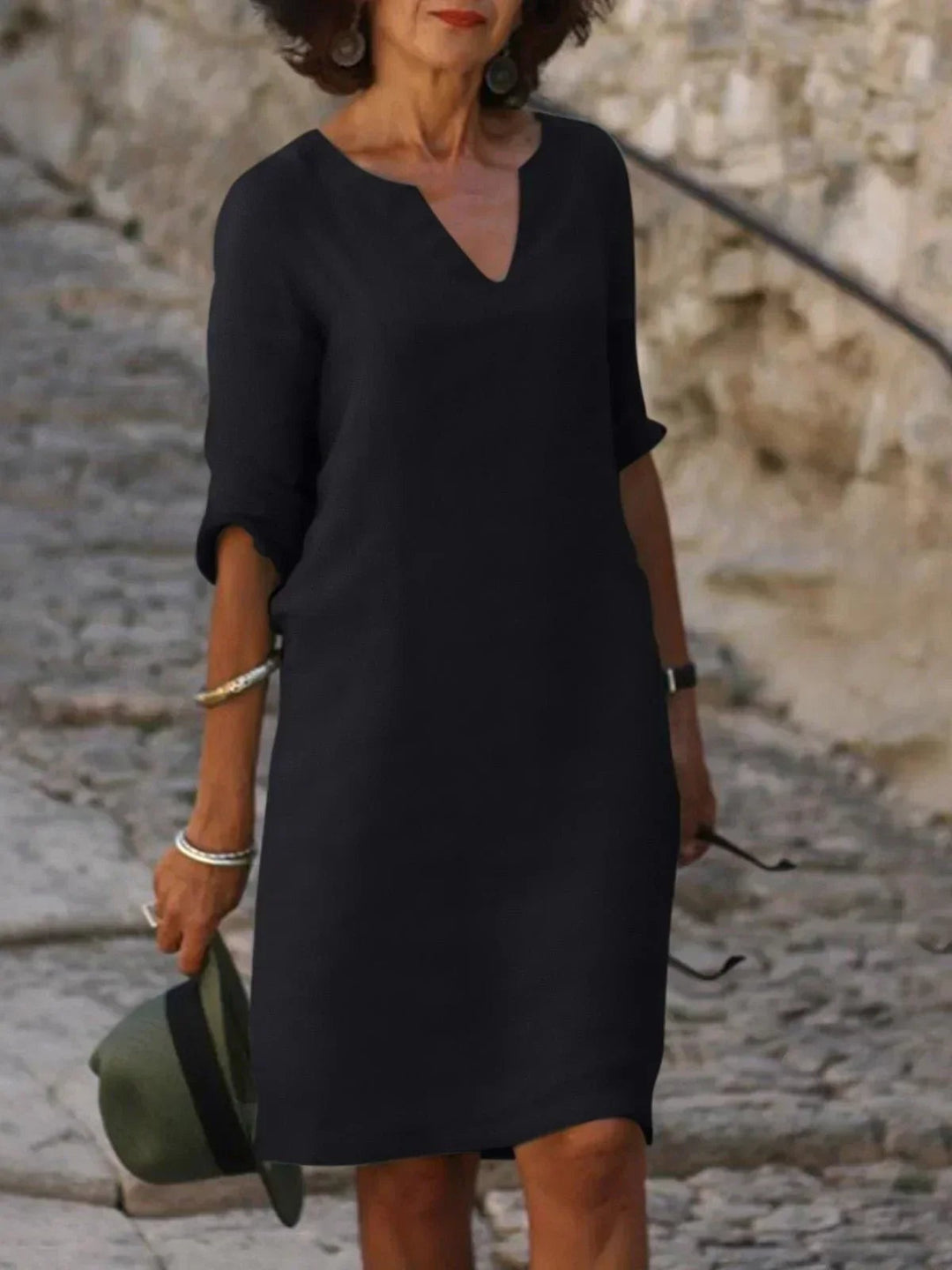 Black notch-neck shift dress with mid-length sleeves, worn on cobbled steps