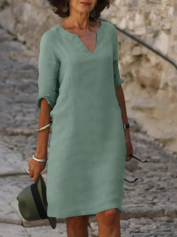 Sage green V-neck midi dress with mid sleeves, styled with a felt hat