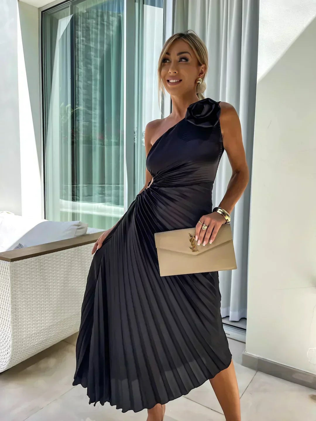 Black satin pleated midi dress with rose trim styled with nude clutch bag