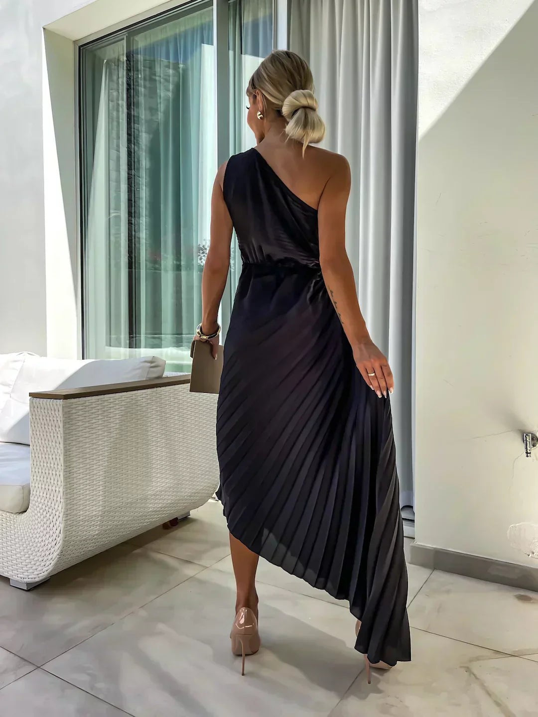 Rear view of black pleated one-shoulder dress with flowing asymmetric hemline
