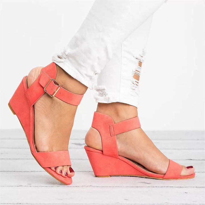 Coral suede wedge sandals featuring ankle strap and gold buckle detail