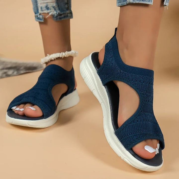 Navy blue sports sandals showing knitted upper and contoured white wedge sole