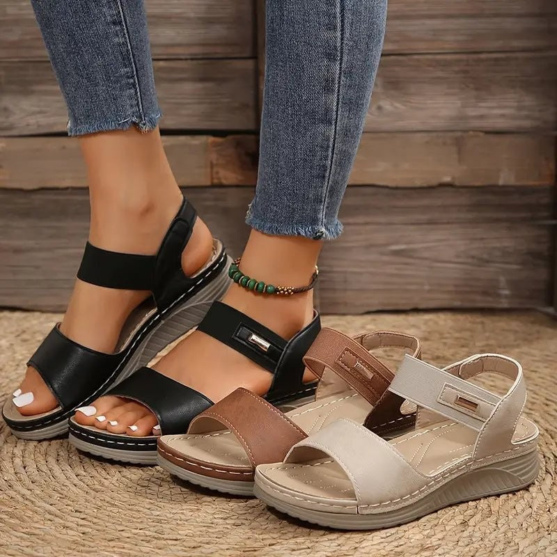 Black, brown and beige wedge sandals lined up showing strap design