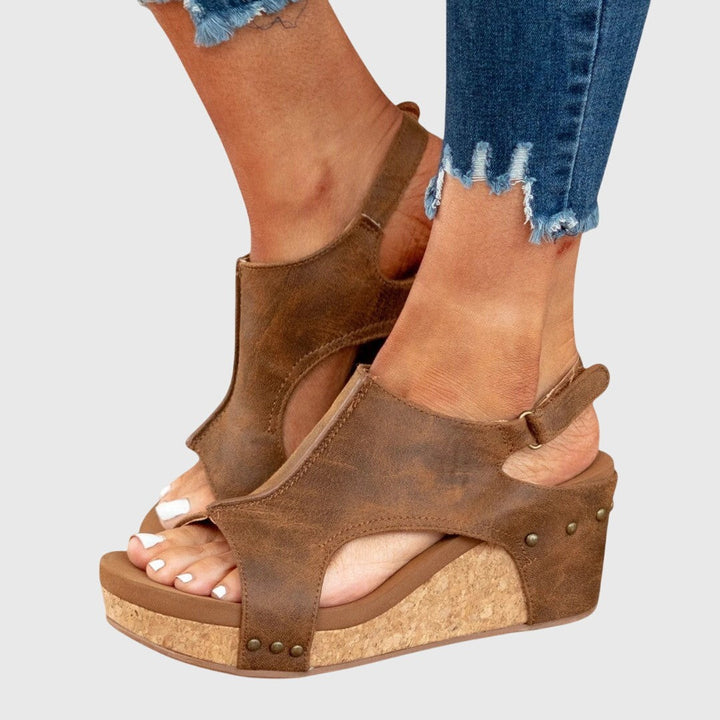 Tan leather shield-style wedge sandals with buckle strap and cork platform sole