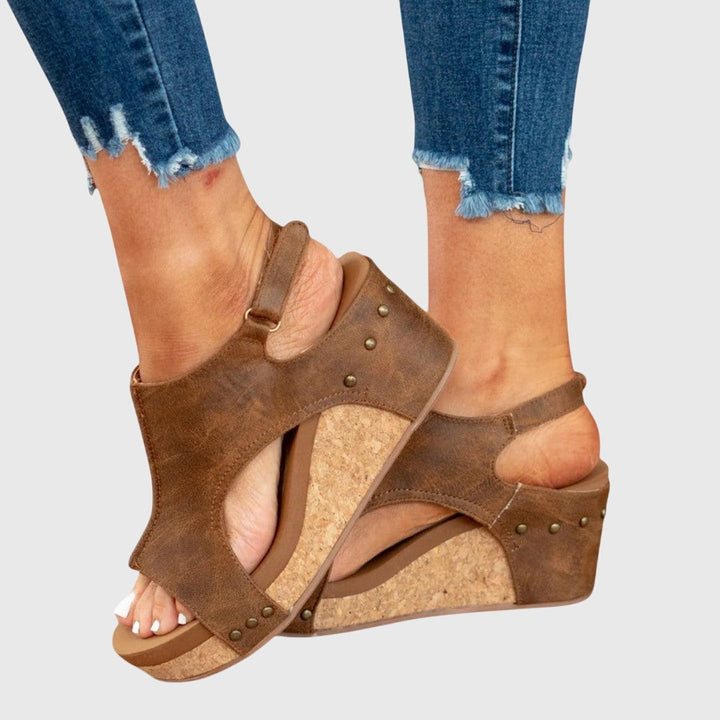 Close-up of brown studded wedge sandals highlighting cork wedge and cutout design