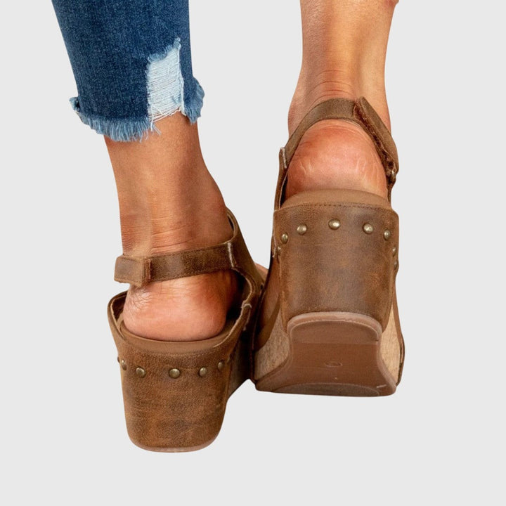 Rear view of tan studded wedge sandals showing ankle strap and cork sole