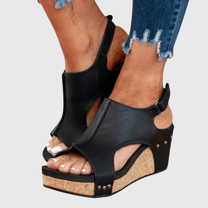 Black studded slingback wedges showing cutout sides and cork wedge heel