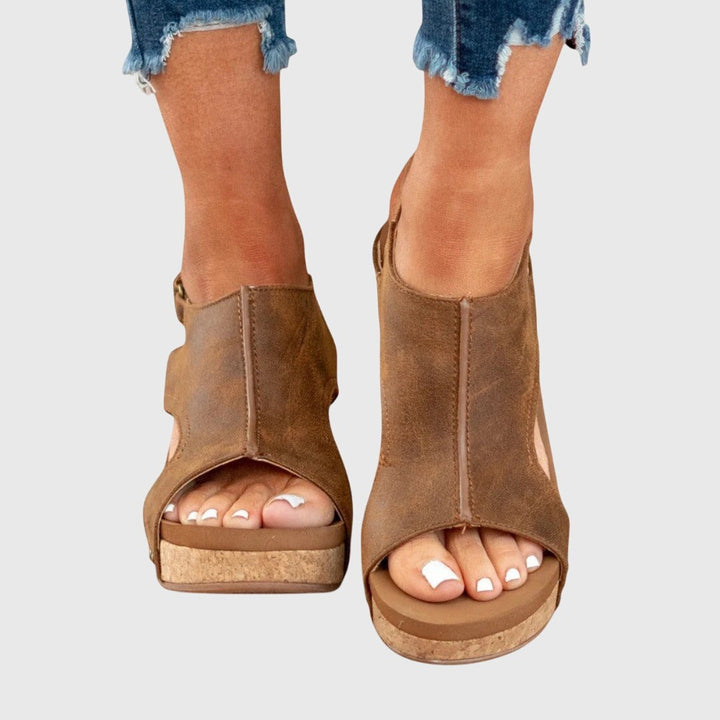 Tan leather peep-toe wedge sandals with cork platform, worn with frayed denim