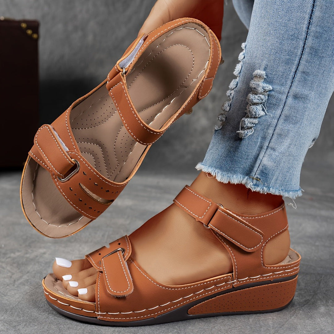 Tan brown wedge sandal with adjustable ankle strap and stitched leather-look upper