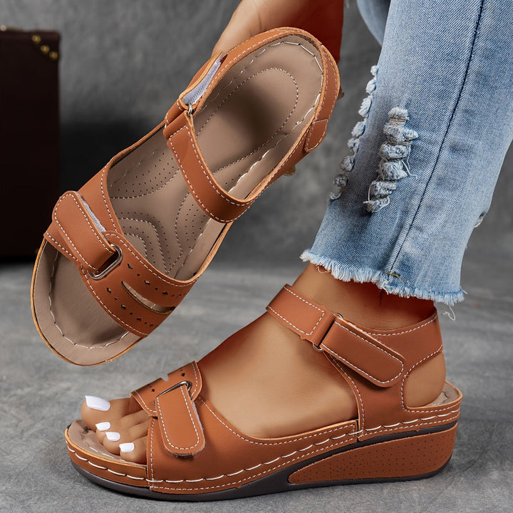 Tan brown wedge sandal with adjustable ankle strap and stitched leather-look upper