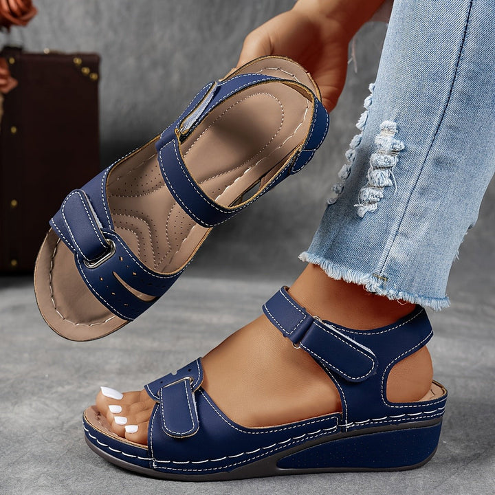 Navy blue open-toe wedge sandal with adjustable straps and cushioned sole