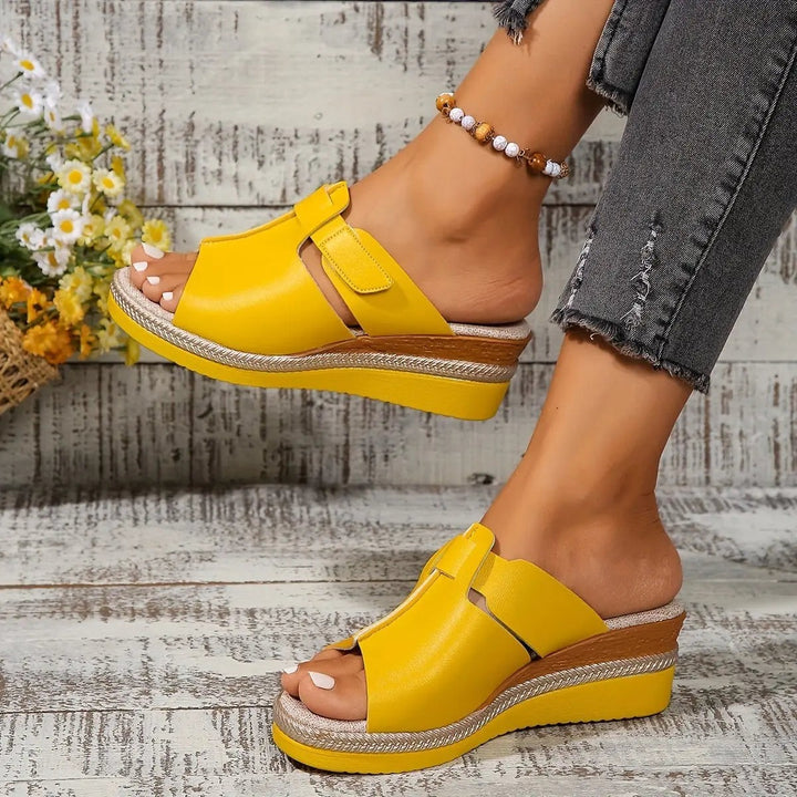 Red wedge sandals worn on foot, showing raised heel and rope trim