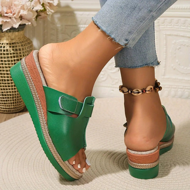 Underside view of green wedge sandal displaying ridged rubber sole and braided trim