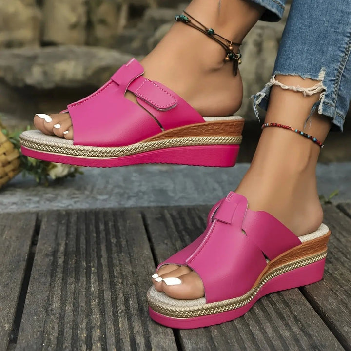 Back view of orange wedge sandals highlighting heel cup and rope-trimmed platform