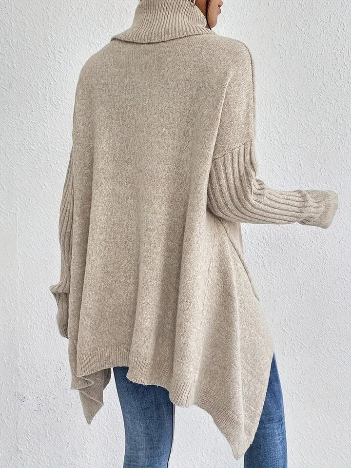 Rear view of beige longline turtleneck sweater with asymmetric handkerchief hem