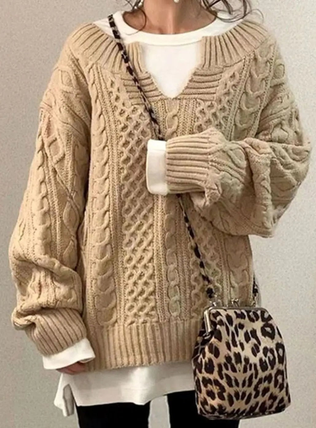 Beige cable knit sweater with oversized fit and layered white vest