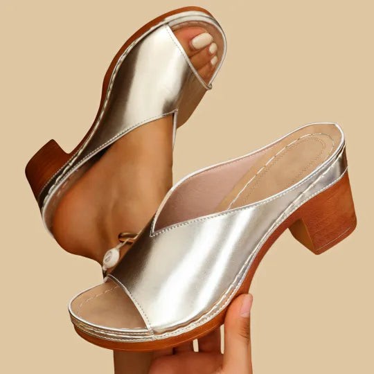 Metallic gold block-heel mule sandals held up, showing platform sole detail
