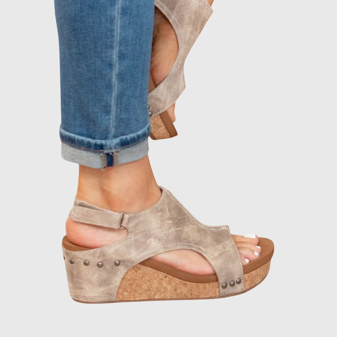 Side profile of taupe wedge sandals with adjustable ankle strap and stud detail