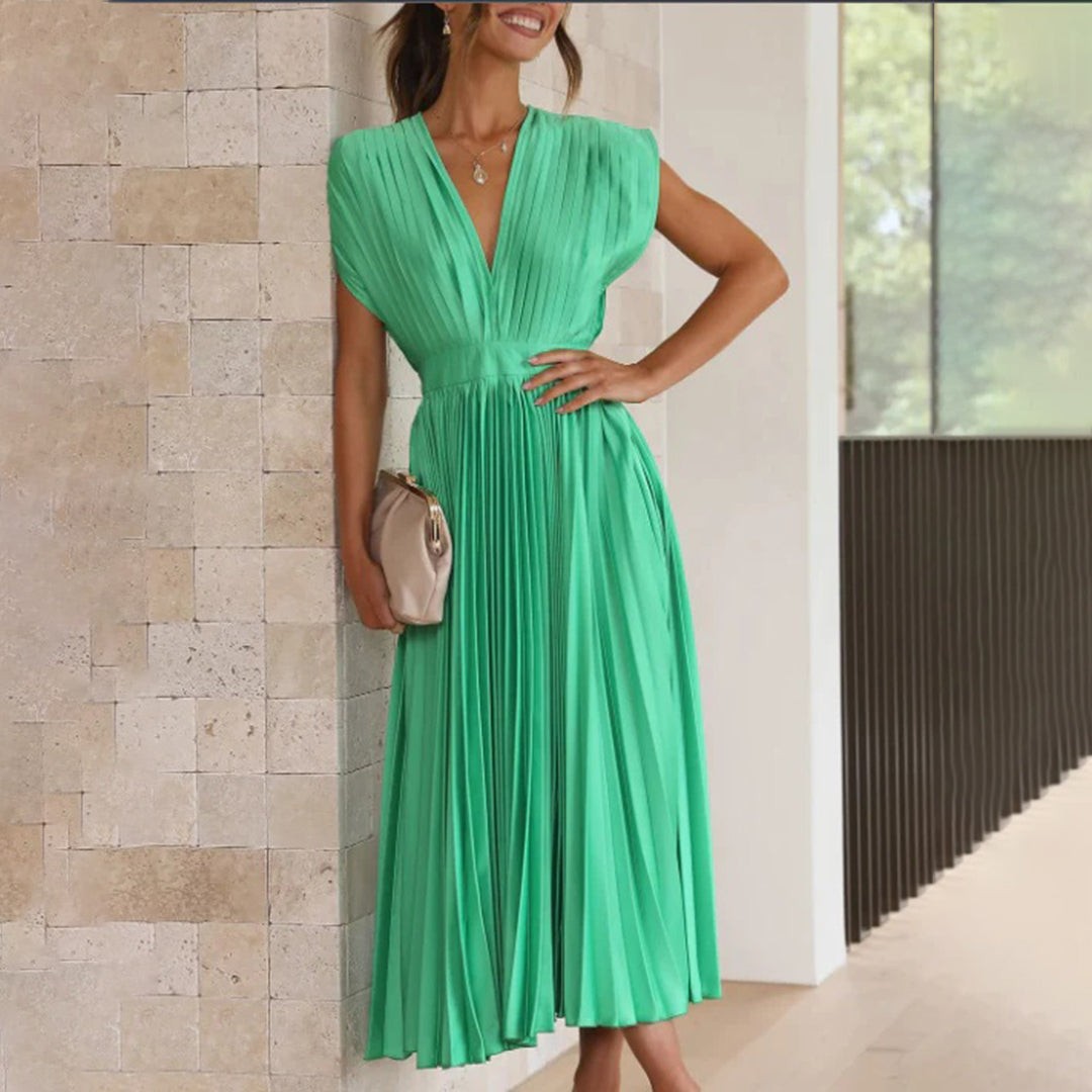 Emerald green pleated midi dress with deep V-neck, paired with clutch