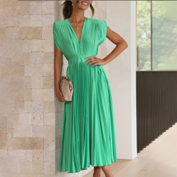 Emerald green pleated midi dress with deep V-neck, paired with clutch