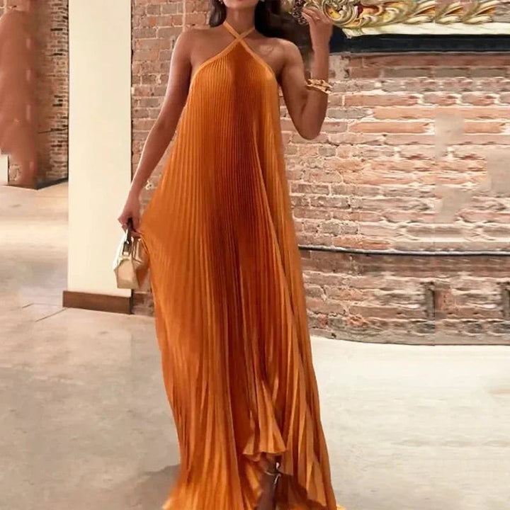 Halter neck maxi dress in pleated satin, styled with a gold clutch bag
