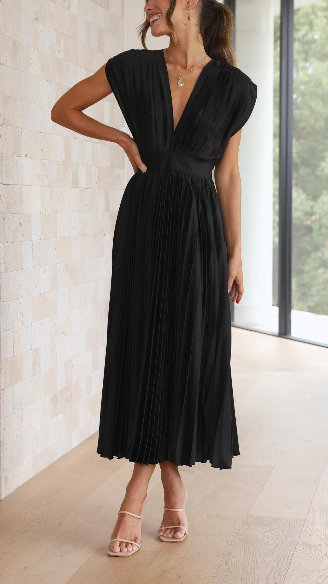 Black pleated maxi dress captured mid-movement showing flowing skirt