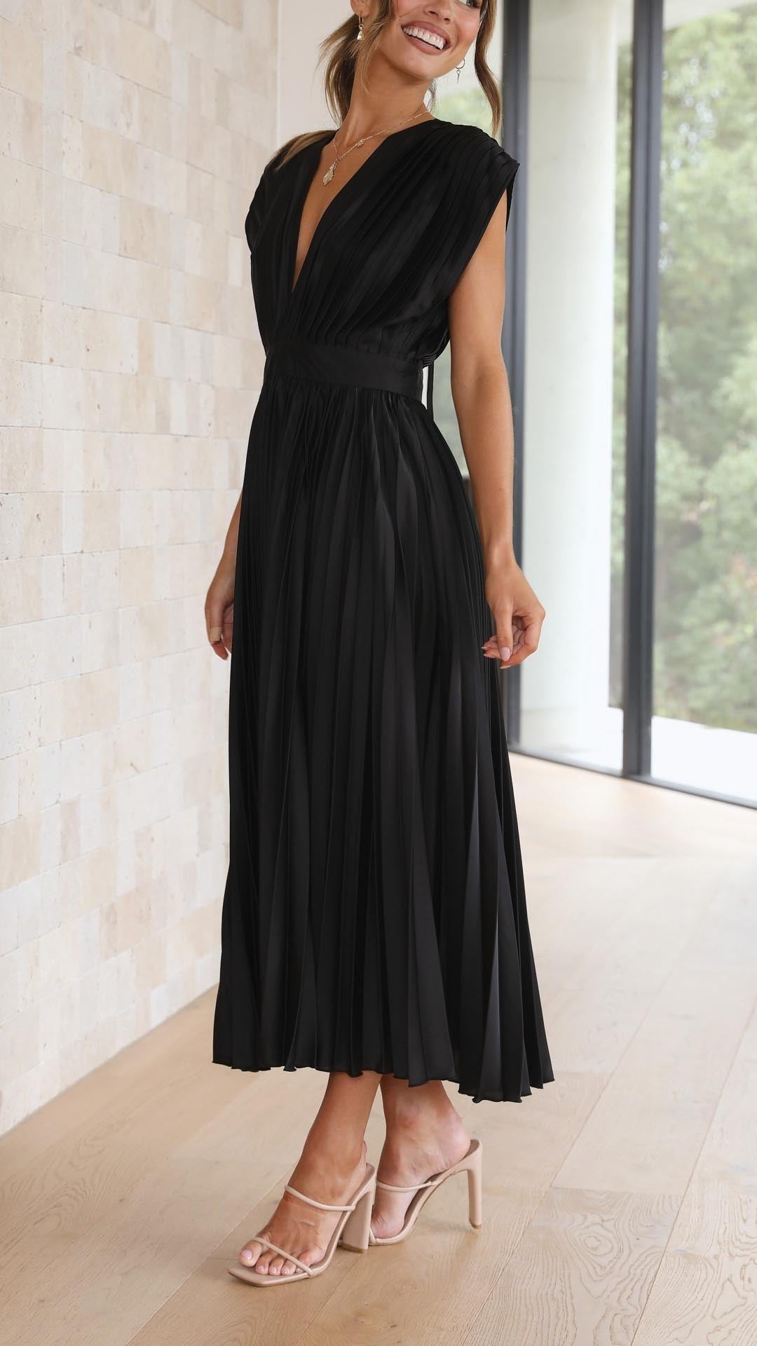 Rear view of black pleated dress showing open back with tie fastening