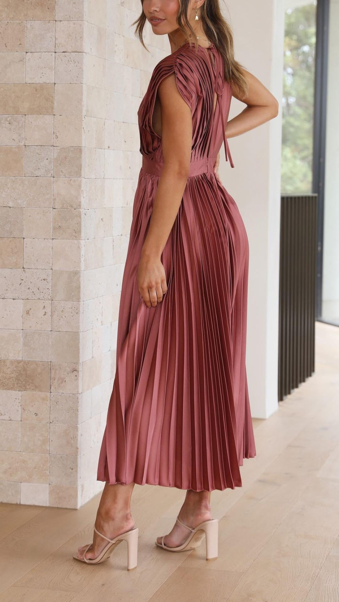 Rear view of rust pleated satin dress highlighting open back and cutout detail