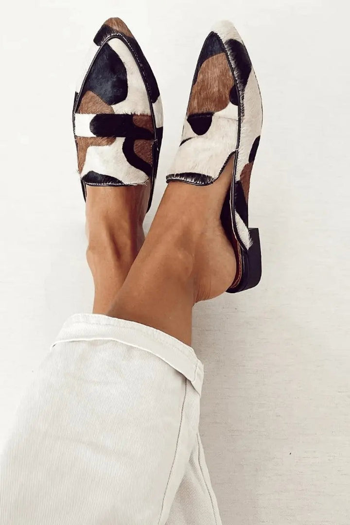 Pointed-toe leather loafers in abstract cow print, worn with cropped white jeans