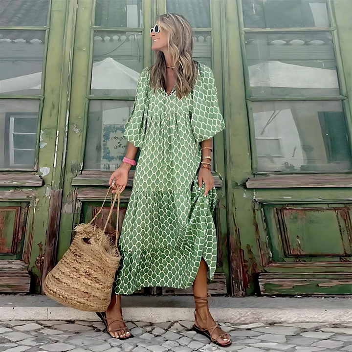 Flowy trellis print maxi dress in green with V-neckline and tiered skirt, worn with strappy sandals