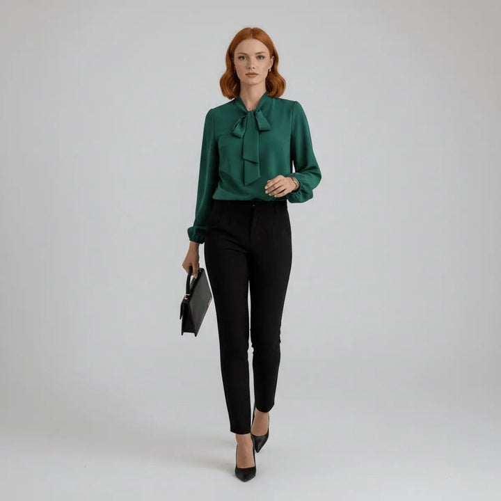 Green pussy-bow blouse worn with black high-waisted trousers, full-length