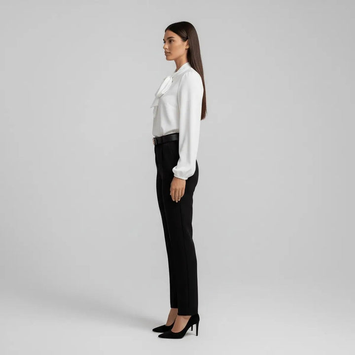 Side profile of ivory bow tie blouse with black high-waisted trousers
