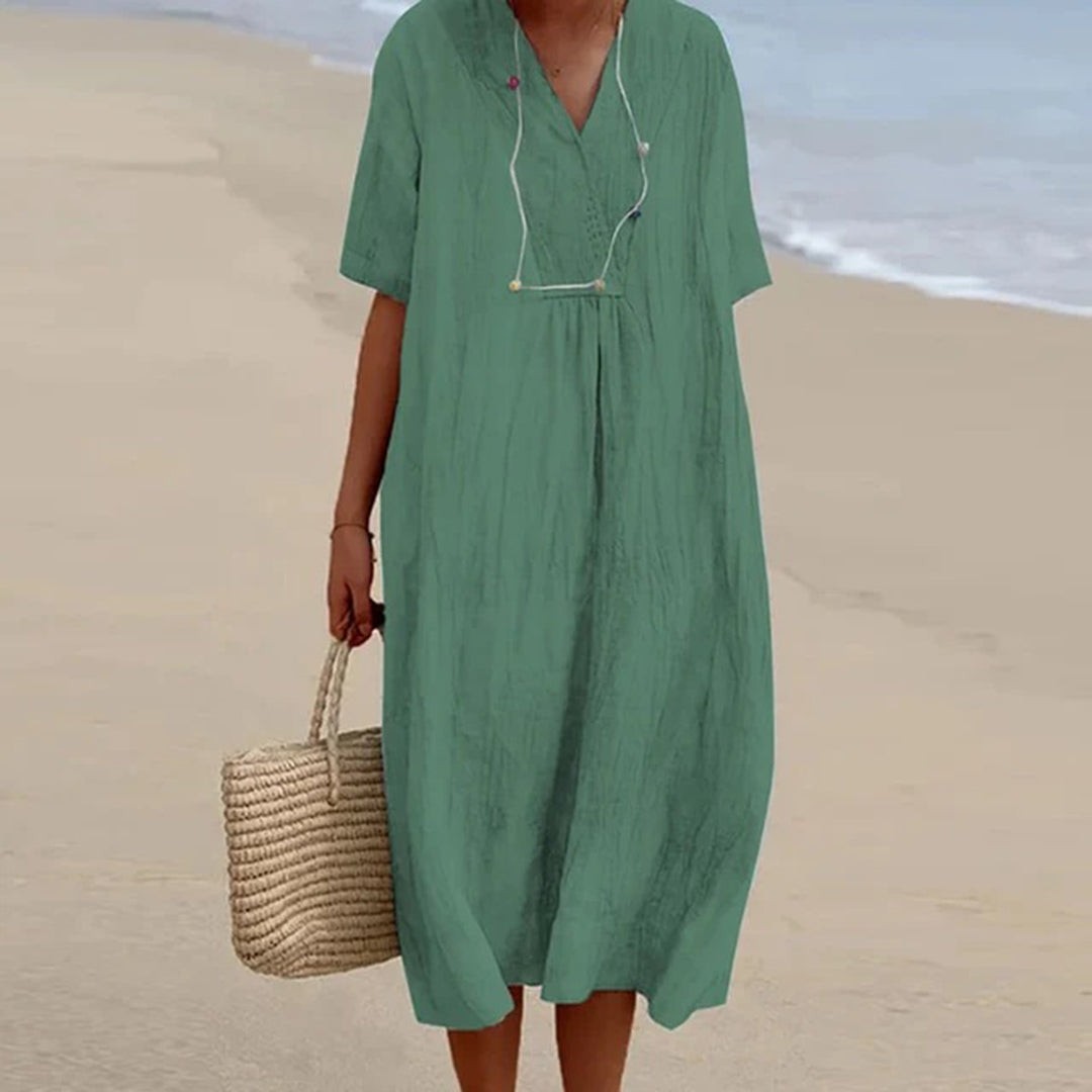 Sage green relaxed-fit midi dress with V-neck, worn with straw tote