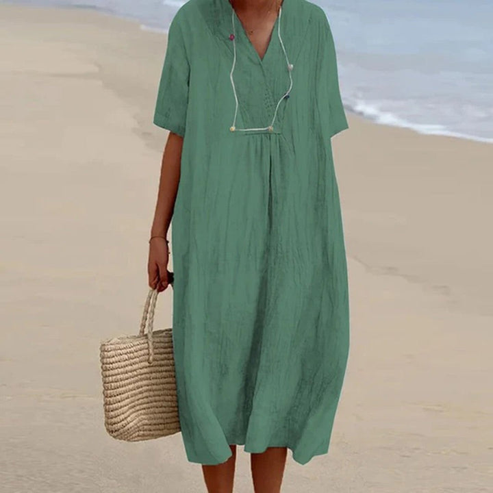 Sage green relaxed-fit midi dress with V-neck, worn with straw tote