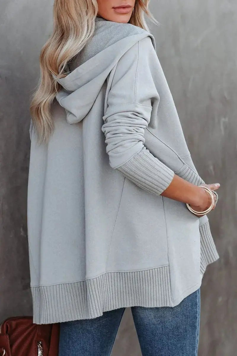 Rear view of grey oversized hoodie showing draped hood and side slits