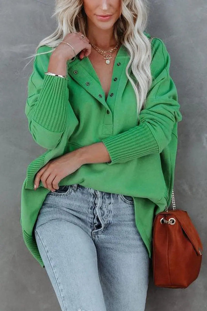 Close-up of green pullover hoodie with popper placket and ribbed cuffs