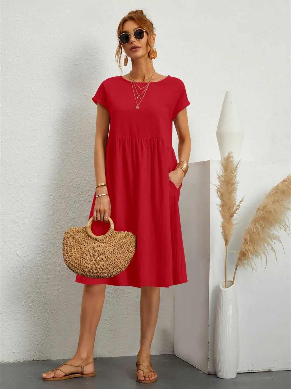 Red midi dress with short sleeves and side pockets, styled with a straw handbag