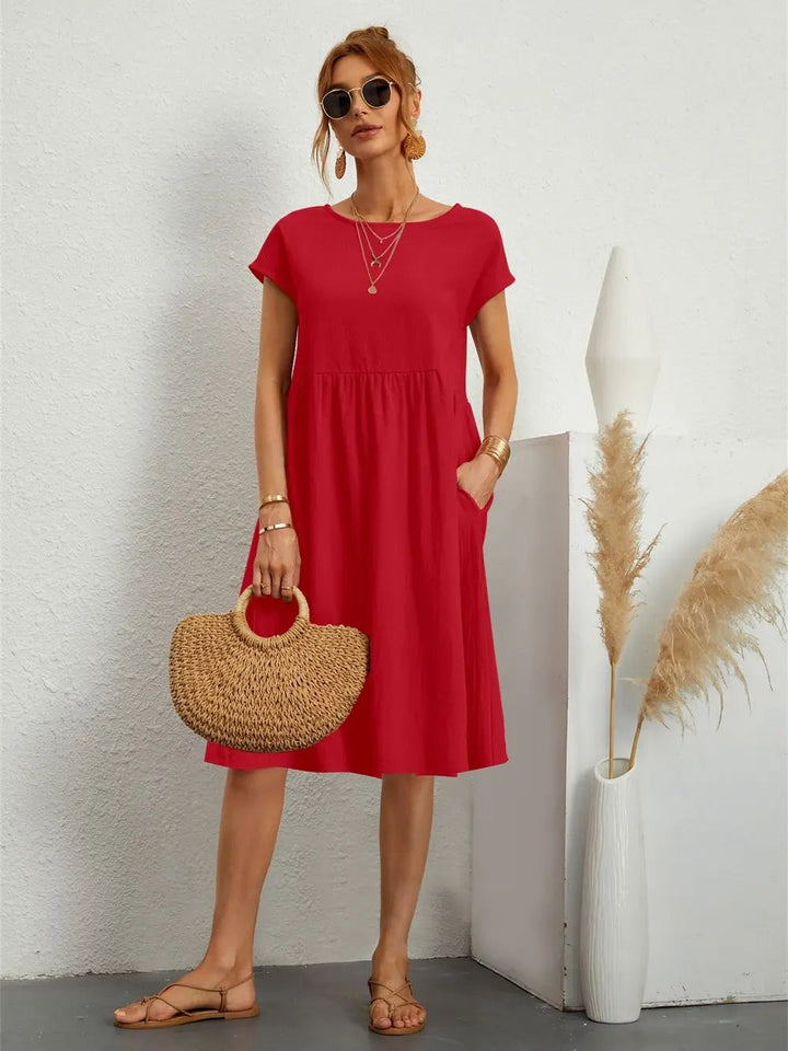 Red midi dress with short sleeves and side pockets, styled with a straw handbag