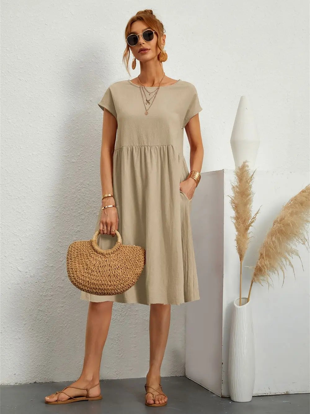 Beige midi dress with short sleeves paired with a woven straw handbag