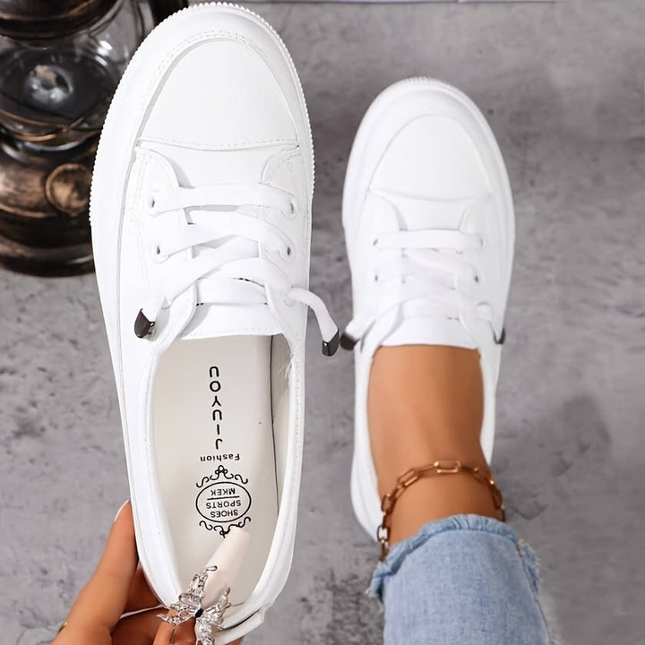 White lace-up trainers with flatform sole, worn on foot with visible insole branding