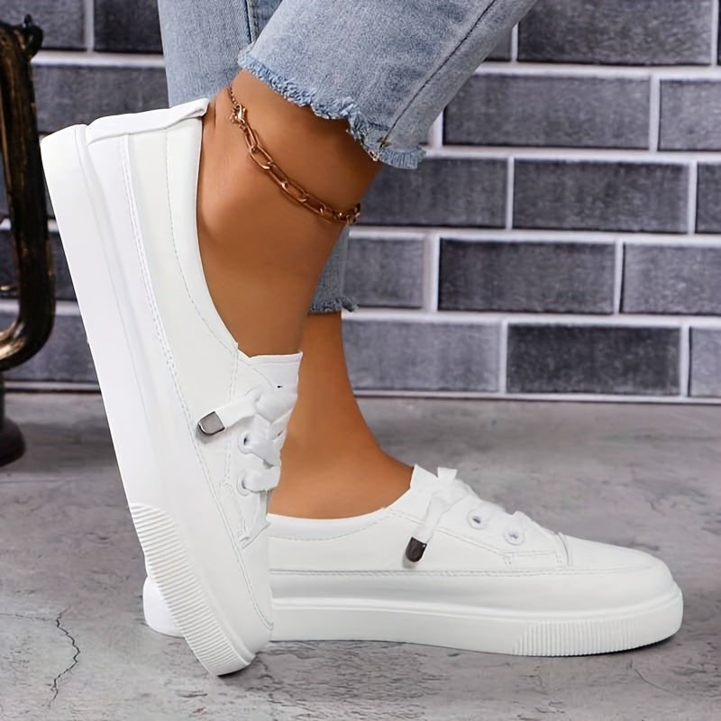 Close-up of white flatform trainers with lace-up front and gold anklet
