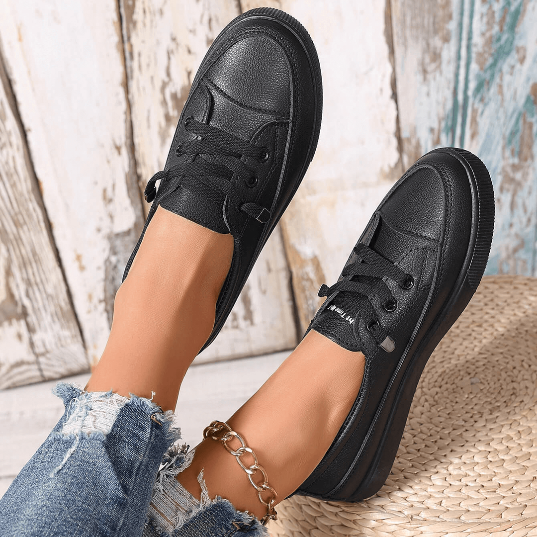 Rear view of black flatform trainers with lace-up fastening and denim outfit