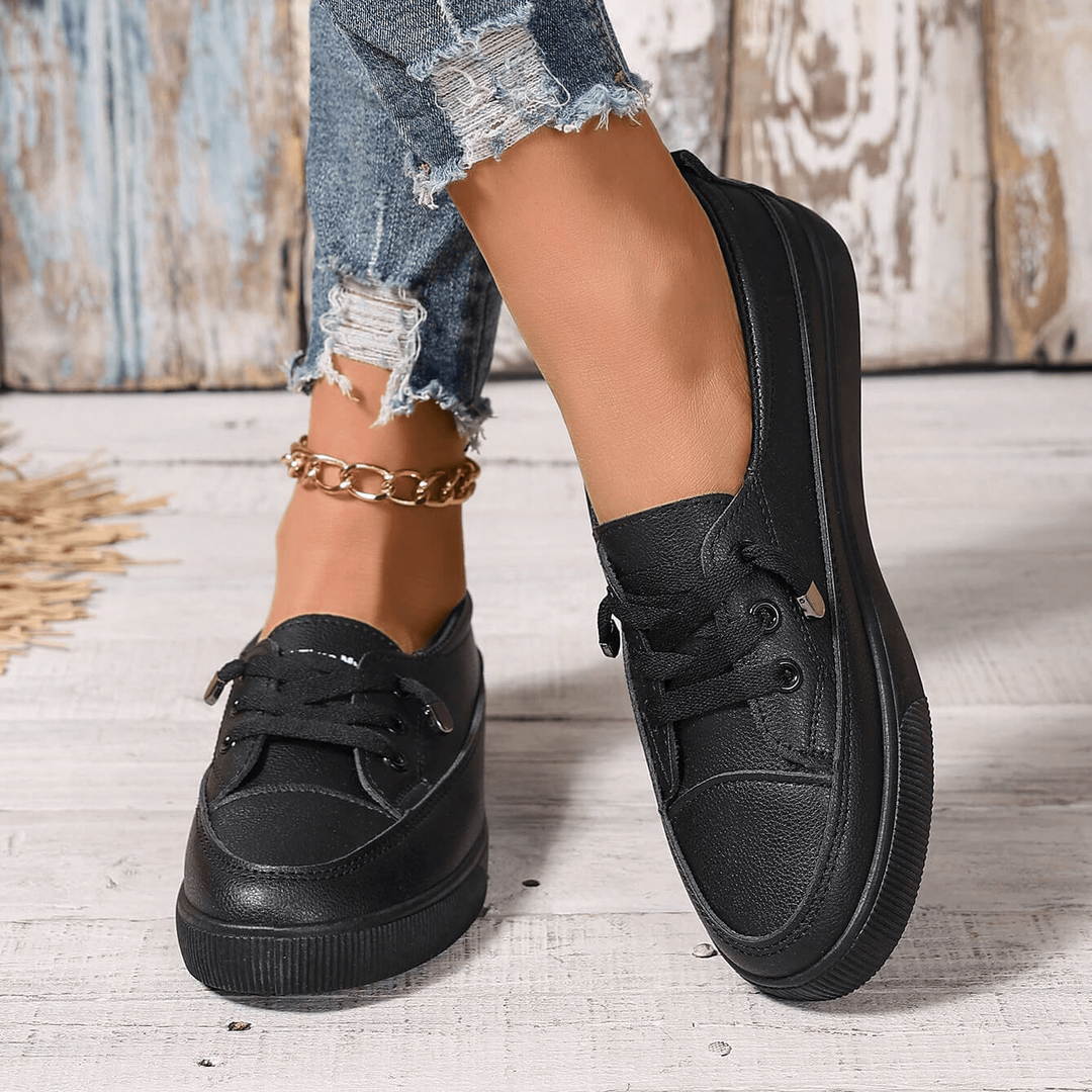 Black lace-up trainers with textured sole, worn with ripped denim jeans