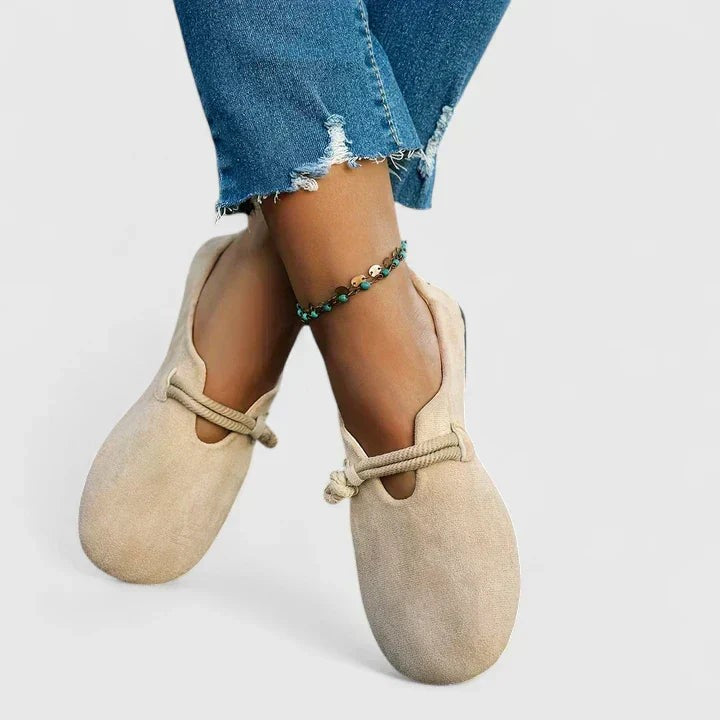 Cream suede loafers with cross-strap rope tie shown on crossed ankles