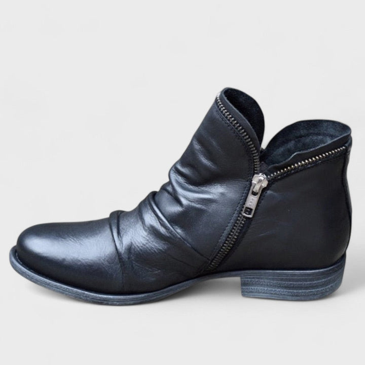 Black leather ankle boot featuring slouchy ruched design and asymmetric zip