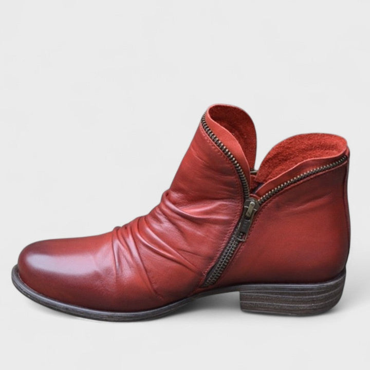Red leather ankle boot showing ruched vamp and antique zip trim