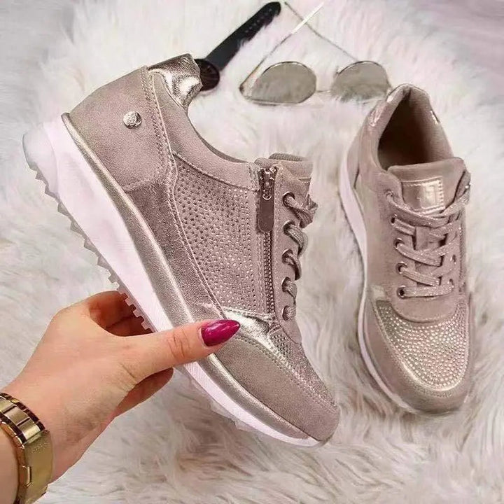 Rose gold zip-up trainers with diamante detailing displayed beside sunglasses
