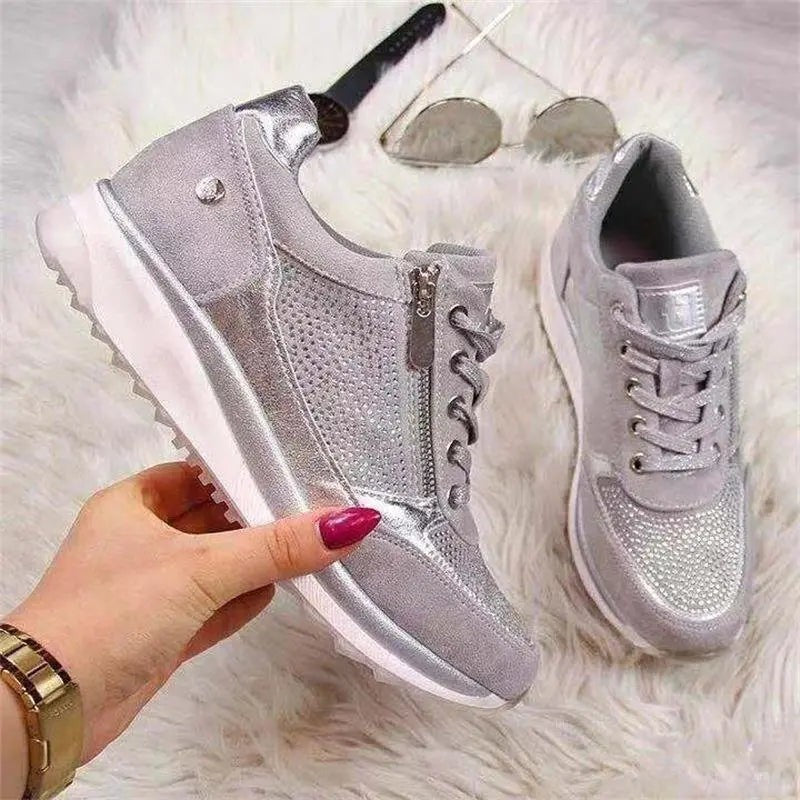 Silver diamante trainers with side zip displayed on faux fur background