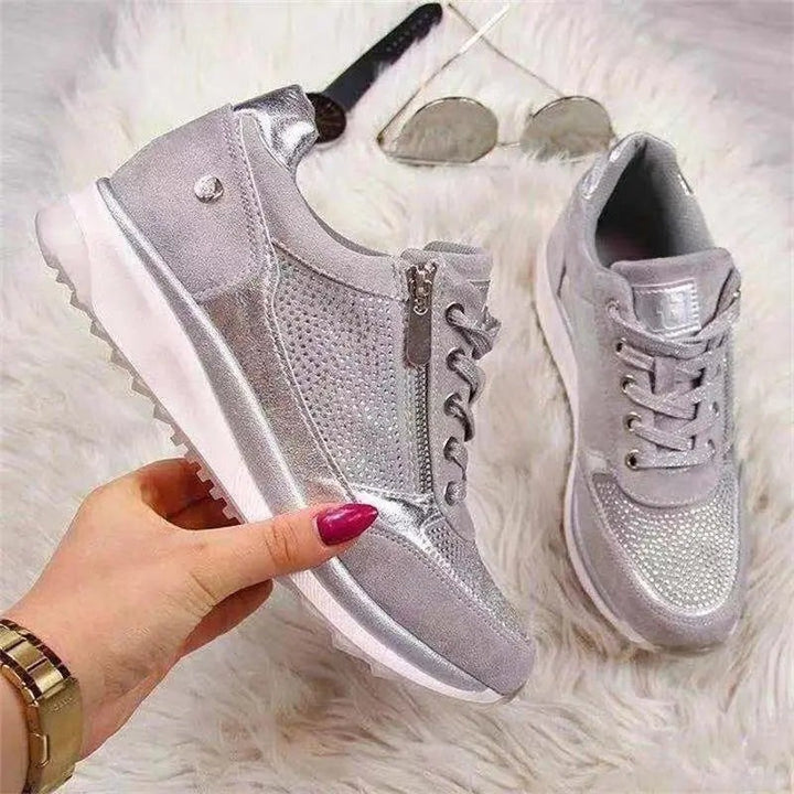 Silver diamante trainers with side zip displayed on faux fur background